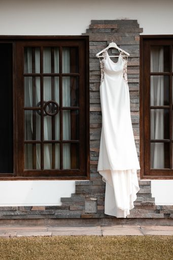 A vertical shot of a gorgeous wedding dress on a hanger, outdoors during daylig