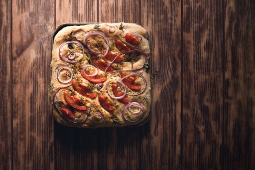 An overhead shot of a square-shaped pizza on a wooden table
