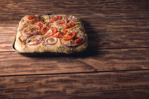 A high angle shot of a square-shaped pizza on a wooden table