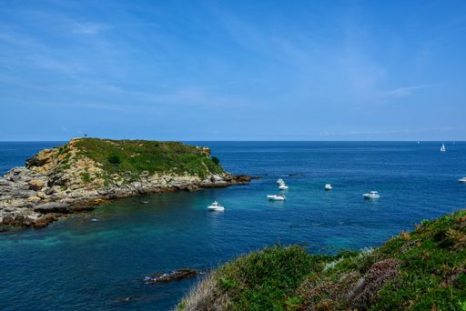 Beach in Basque Country, bay with boats with crystal clear waters next to large rocks