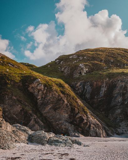 A vertical shot of beautiful green mountains under the breathtaking cloudy sky during daytime