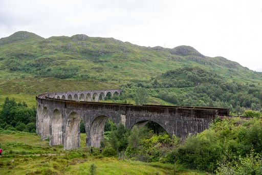 An aerial shot of Glenfinnan Viaduct railway in background of greenery mountains