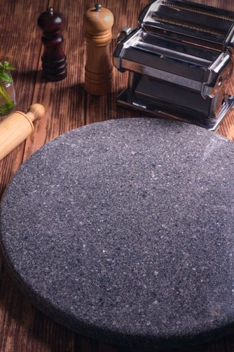 A vertical shot of a circular marble surface with dough rollers on a wooden table