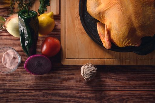 A top view of uncooked chicken with vegetable ingredients on the side