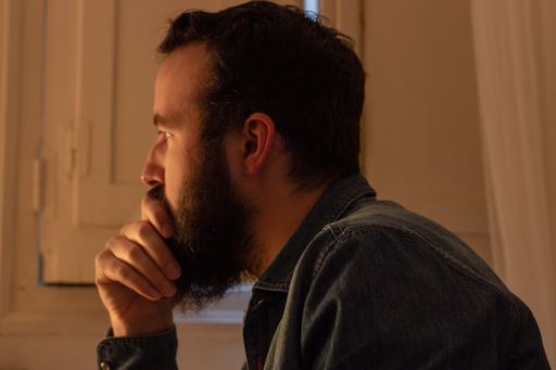 An attractive bearded man thinking about something with his hand on his mouth