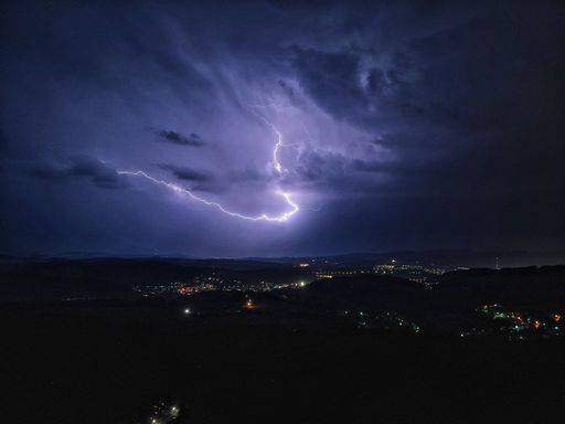 A beautiful shot of lightning strike in the night sky over the city on a stormy night