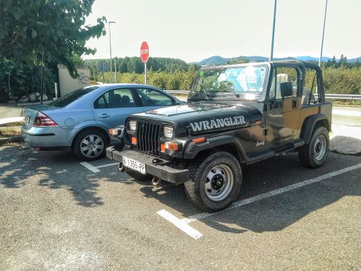 A closeup of Classic and typical off road SUV, model of '90s Jeep Wrangler in the parking spot