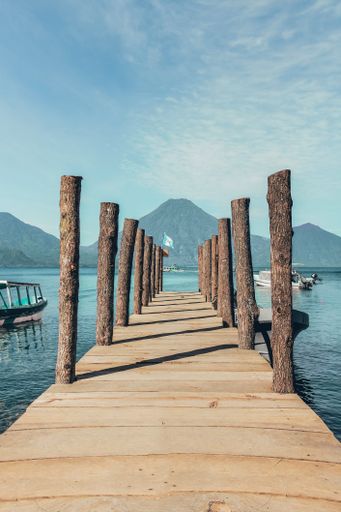 A vertical closeup shot of a pier on the lake with mountains on the background
