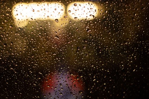 A closeup shot of a raindrops on glass after rain in orange tone