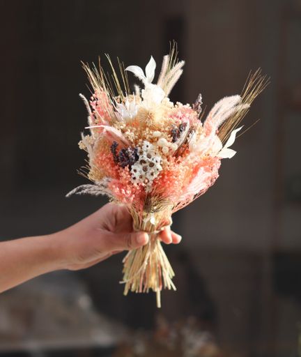 Picture of Woman's Hand Holding a Bouquet of Dried Flowers of Different Types and Colors Pink White and Purple