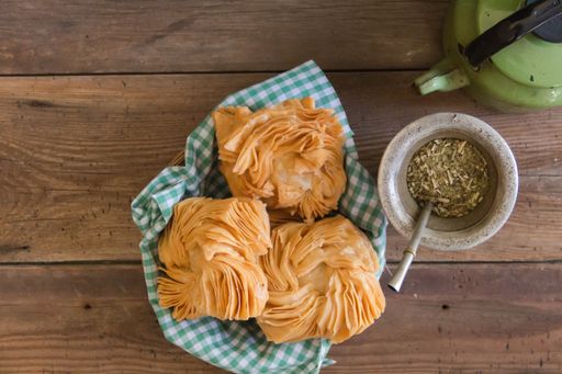 An overhead shot of mate and fried sweet potato and quince pastries on a wooden table