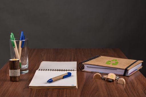 A closeup of eco pens and notepads on the table with a USB flash drive - environmental concept