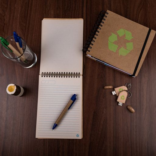 A high angle view of eco pens, notepads and a USB flash drive on the table - environmental concept