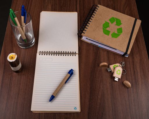 A high angle view of eco pens, notepads and a USB flash drive on the table - environmental concept