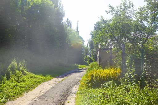 A beautiful shot of a pathway inteh middle of buildings and trees in Russian