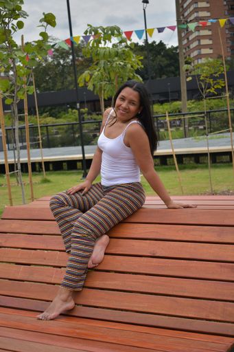 A vertical closeup shot of a Latin brunette sitting on the bench and smiling at the camera