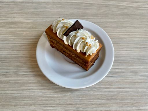 Closeup shot of a delicious Toffee cake with cream and piece of chocolateon a white plate
