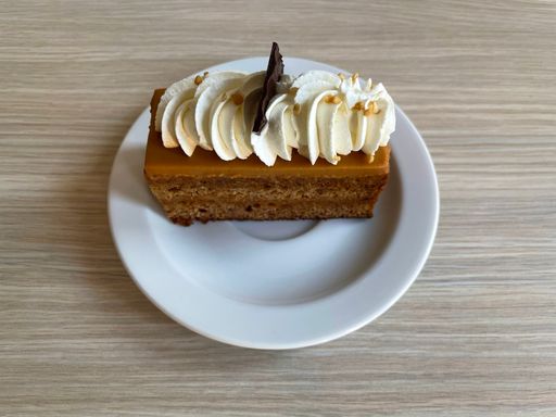 Closeup shot of a delicious Toffee cake with cream and piece of chocolate on a white plate
