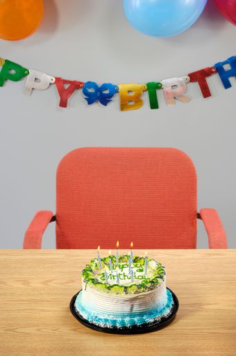 A vertical shot of a birthday cake on the wooden table in the background of decorations