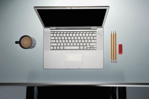 A top view of a laptop next to a cup of coffee and pencils