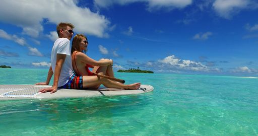 A Caucasian couple boarding on a paddleboard in Rasdhoo Island, The Maldives