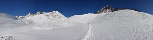 A panoramic view of beautiful mountains covered in snow against a blue sky