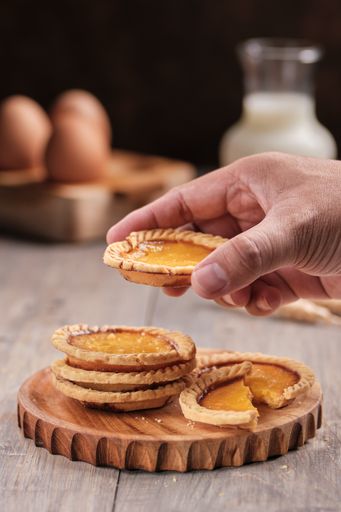 A vertical selective focus shot of a male holding a piece of a biscuit with ingredients on the side
