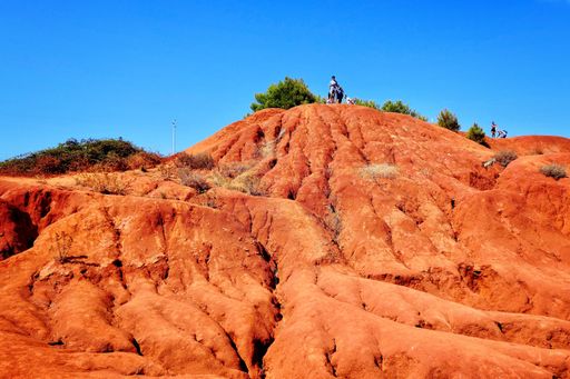 A low angle shot of a person standing on top of the deserted mountain with a clear sky in the background