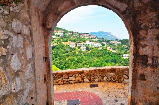 A view of a hill station through an old arched door