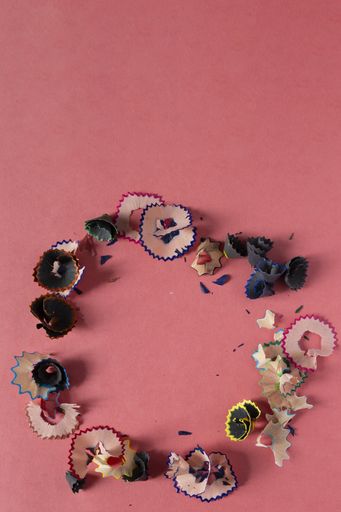 A vertical high angle shot of circle made of pencil shavings on a pink background