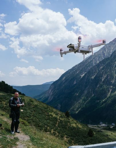 A caucasian man in a motorcycle suit with a drone in the Pyrenees