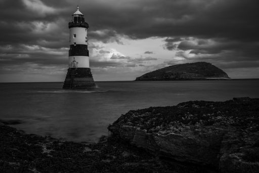 A beautiful view of a lighthouse in the ocean with a cloudy sky background