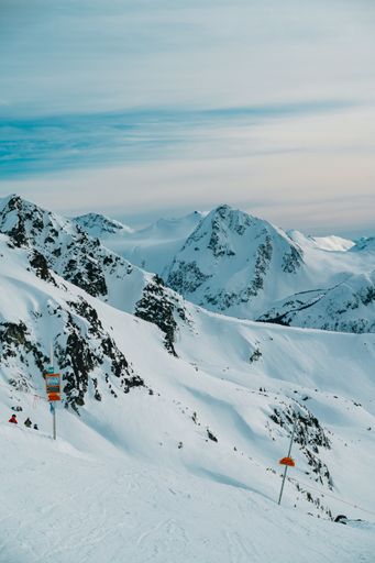 A vertical shot of a mountain range covered with snow against a cloudy sky
