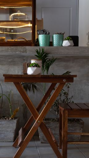 vertical photo of a table with two wooden chairs along with some plants inside a coffee shop in tulum mexico. High quality photo