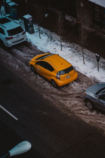 A vertical shot of a yellow Toyota car parked on the street during winter in Vancouver, Canada