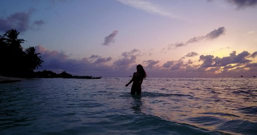 A Caucasian woman relaxing in the water of the ocean with a background of a beautiful sunset