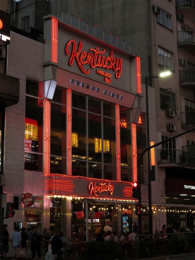 A vertical shot of the facade of the Kentucky Pizzeria at night in Buenos Aires, Argentina
