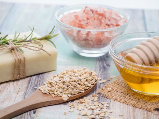 A closeup shot of natural skincare product ingredients: natural soap, oat flakes, honey, and sea salt