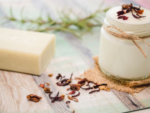 A closeup shot of natural skincare product ingredients: natural soap, yogurt, and herbs