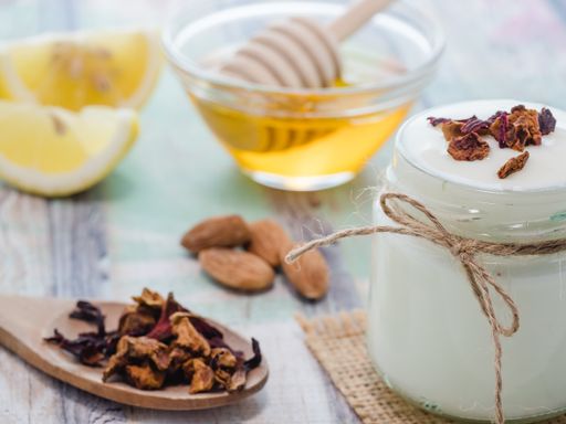 A closeup shot of natural skincare product ingredients: lemon, honey, yogurt and almonds