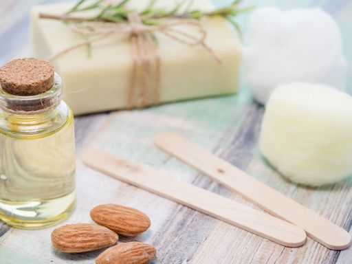 A closeup shot of natural skincare product ingredients: essential oil, almonds, and natural soap