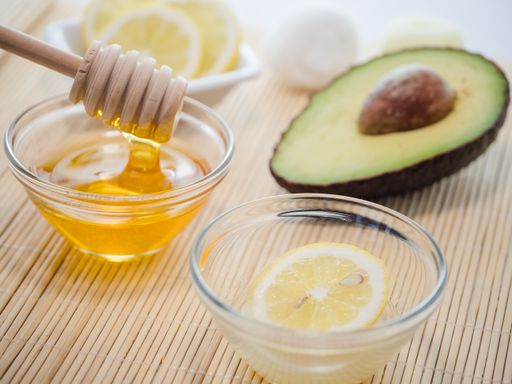 A closeup shot of natural skincare product ingredients: honey, lemon, and avocado