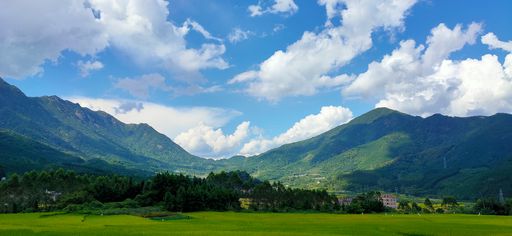 A beautiful view of green hills and white clouds in the sky