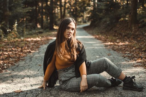 A brunette young female sitting on the road in the park