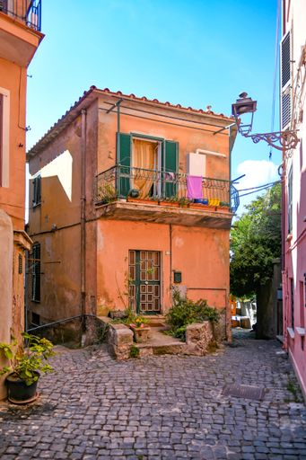A vertical shot of the old orange building's facade against the blue sky. Nemi, Lazio, Italy.