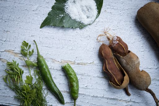Some raw tamarind with tamarind leaf in a wooden bench with sunlight.