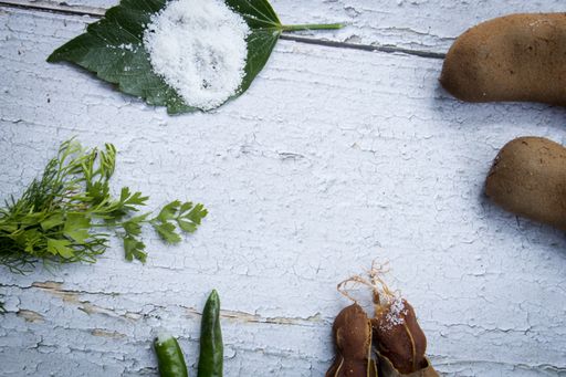 Some raw tamarind with tamarind leaf in a wooden bench with sunlight.