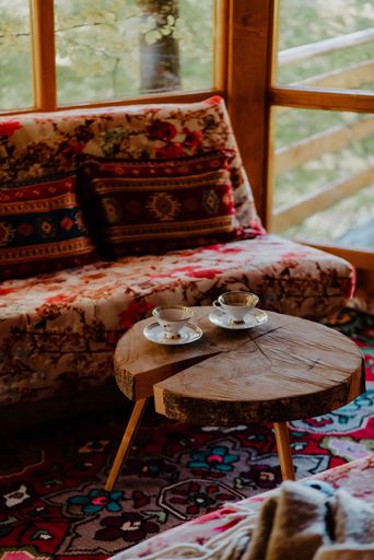 A vertical shot of a couch, a small coffee table with two cups on it, and a beautiful carpet below