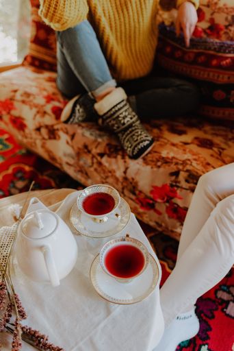 A selective focus shot of two cups of tea on a table with a white teapot beside