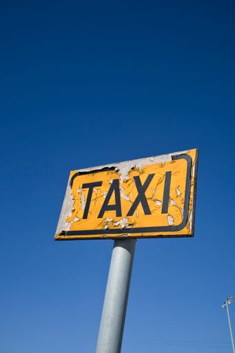 weathered old Taxi signpost outdoors against blue